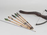 a bow, arrows and a bow rest on a white surface