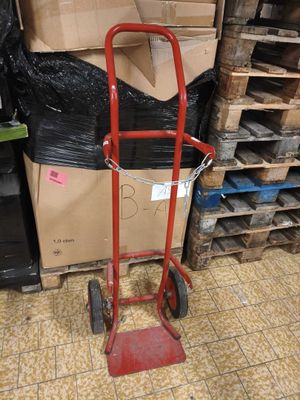 a red hand truck that is next to a pile of boxes