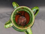 a green vase that has a brown substance in it