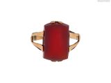 un gros plan d'une bague en pierre rouge sur fond blanc