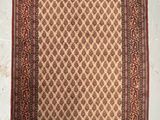 un tapis marron et rouge accroché au mur, à côté d'un mur blanc