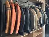 a lot of jackets hanging on a rack in a room