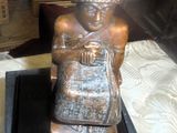 une statue en bronze représentant un homme assis sur une table