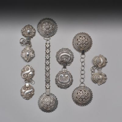 Plusieurs bijoux en argent sont exposés sur une surface blanche