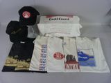 Plusieurs t-shirts, casquettes et autres articles sont disposés sur une table