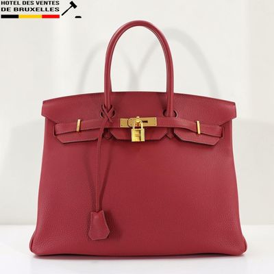 un sac à main en cuir rouge muni d'un fermoir doré sur la poignée