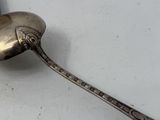 a silver spoon with a handle on a white surface