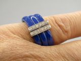 a woman ' s hand holding a blue ring with diamonds on it