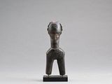 une statue représentant une femme, dont la tête repose sur un socle en bois