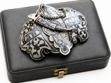 a black box with a silver brooch on top of it
