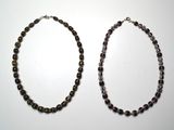 deux colliers composés de perles vertes et noires sur un fond blanc