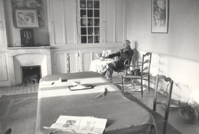 black and white photograph of a man sitting in a chair in a bedroom