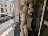 a statue of a boy holding a baby in his arms on the sidewalk