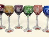 six wine glasses lined up in a row on a white surface