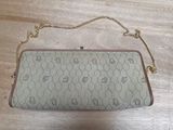 a white purse with a chain on it sitting on a wooden floor