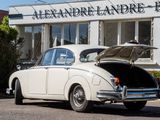 a white car with its trunk open in front of a building
