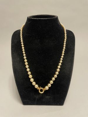 un collier de perles muni d'un fermoir en or, posé sur un mannequin