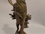 statue en bronze d'une femme tenant un oiseau sur une base en bois
