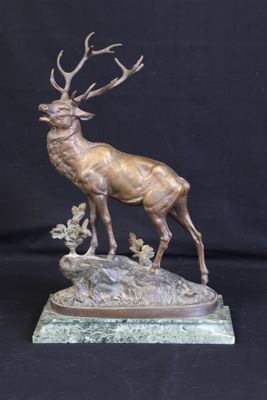 bronze sculpture of a stag on a rock with a black background