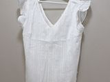 sleeveless white top with ruffles on the shoulders