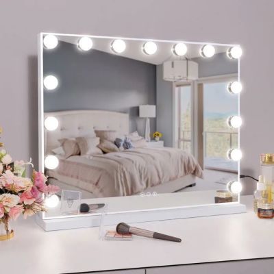 a white vanity with a mirror and lights on it