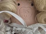 a close up of a doll with blonde hair and a white dress