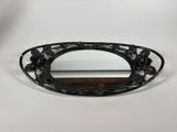 an oval shaped mirror with a black frame and flowers on it