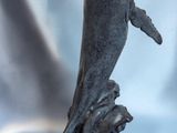 statue représentant un dauphin bondissant hors de l'eau, posée sur un socle noir