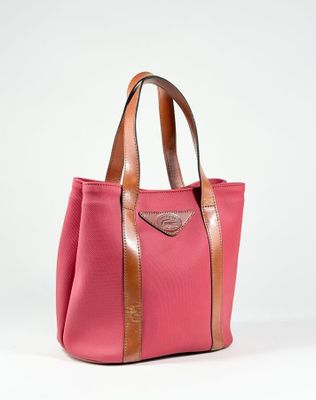 un sac fourre-tout rose et marron posé sur une surface blanche