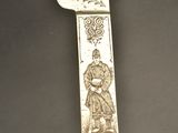 a silver knife with a design on it on a table