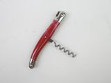 a corkscrew with a red handle laying on a white surface