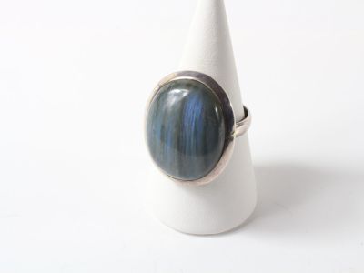 silver ring with a blue stone in the middle of it on a white cone
