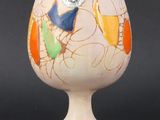 a white vase with colorful designs on it on a black surface