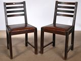 pair of wooden chairs with leather seat and backrests