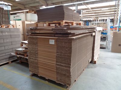 a large stack of boxes in a warehouse with pallets of wood