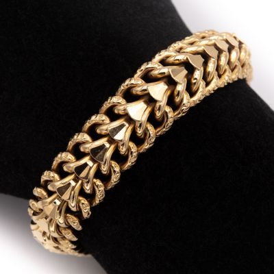 un gros plan d'un bracelet en or posé sur une serviette