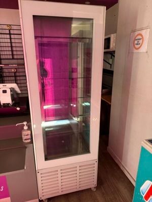 un réfrigérateur avec une porte vitrée, placé dans un coin de la pièce