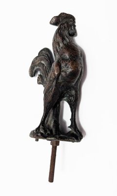 une statue représentant un coq sur un bâton, sur fond blanc