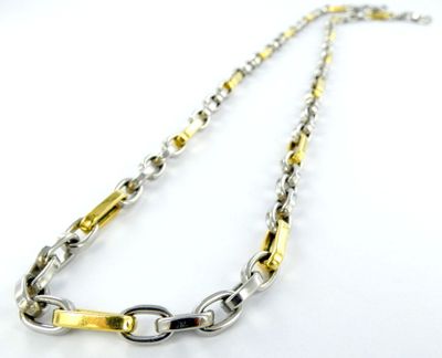 un gros plan d'un collier en argent et en or posé sur une surface blanche