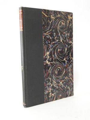 an old book with a black cover and a red and gold swirl design