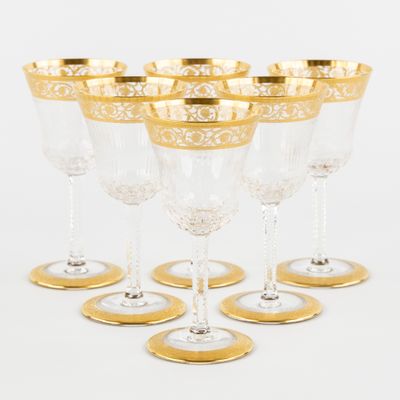 six verres à vin à bord doré sont alignés en rangée
