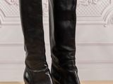 black leather boots on a wooden table in front of a wall