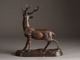 bronze sculpture of a stag standing on a base on a gray background