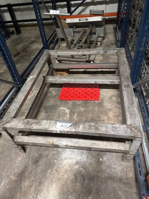 une table en métal recouverte d'un tapis rouge, dans un entrepôt