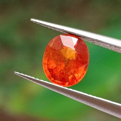 a close up of an orange diamond being held by a pair of pliers