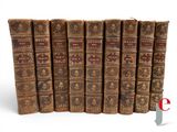 several old books are lined up in a row on a white surface