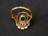 an image of a gold ring with a green stone