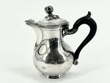 une théière en argent avec une anse noire sur fond blanc