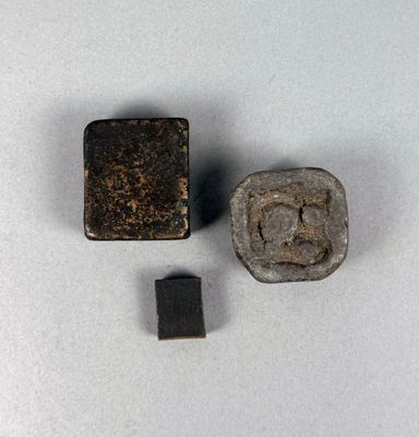 deux morceaux de métal et un objet métallique carré posés sur une surface blanche