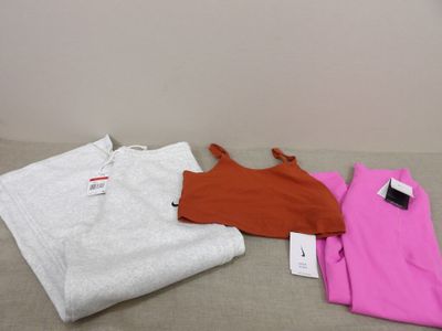 trois paires de vêtements sont disposées sur un lit